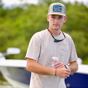 Man holding a can of Coors Light by a boat on a lake