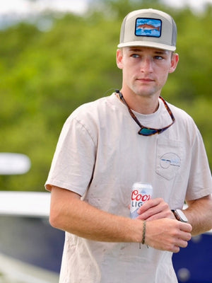Man holding a can of Coors Light by a boat on a lake