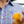 Person wearing a blue and red checkered shirt with a brand logo, holding a blurred object.