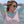 Woman wearing a patterned long-sleeve shirt and sunglasses on a boat with water and sky in the background