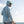 Man wearing a light gray hoodie and sunglasses, standing on a boat with water and sky in the background.