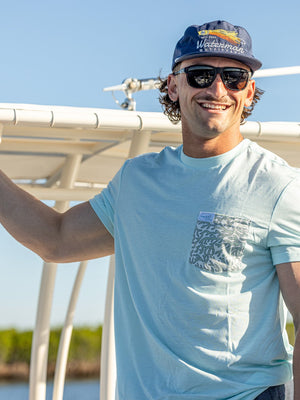 Man on a boat wearing sunglasses and a cap with a clear sky background