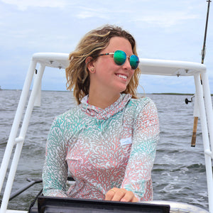 Woman on a boat wearing sunglasses with a scenic background