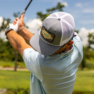 Man playing golf on a sunny day with trees in the background
