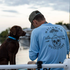 Man and dog on a dock wearing a 'Waterman Outfitters' shirt