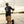 Man fishing on a boat with a dog by his side, wearing a black shirt with white text and graphics.