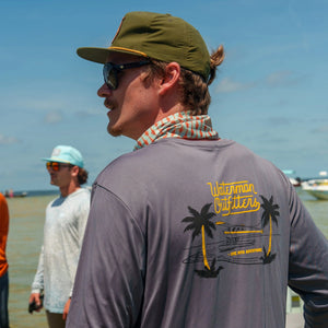 Man wearing a gray long-sleeve shirt with a brand logo on the beach