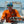 Man on a boat wearing an orange shirt and blue cap, holding a fishing rod.