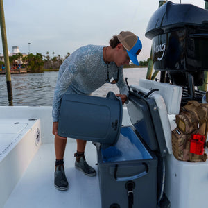 Person on a boat using a cooler box with a scenic background