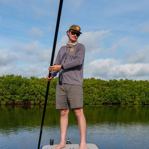 Person on a paddleboard with mangroves and blue sky in the background