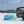 Fishing reel, cap, and tackle box on a boat with water and sky in the background
