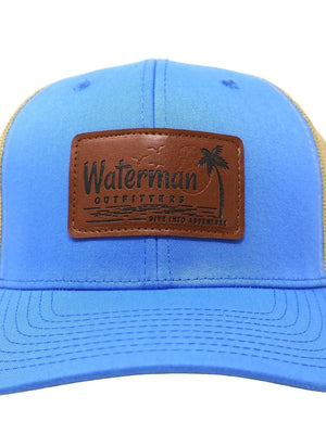 Blue and beige cap with a leather patch featuring 'Waterman Outfitters' on a white background