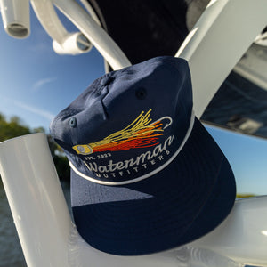 Navy blue cap with a logo on a boat railing with water and sky in the background