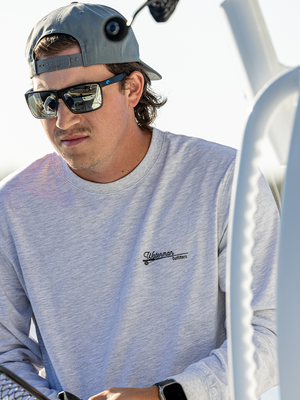 Man wearing a light gray sweatshirt with a logo, sunglasses, and a cap on a boat.