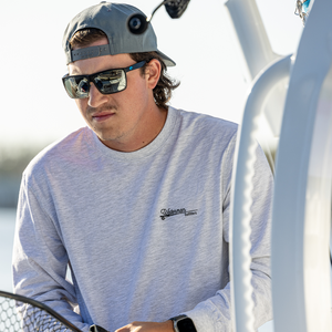 Man wearing a light gray sweatshirt with a logo, sunglasses, and a cap on a boat.